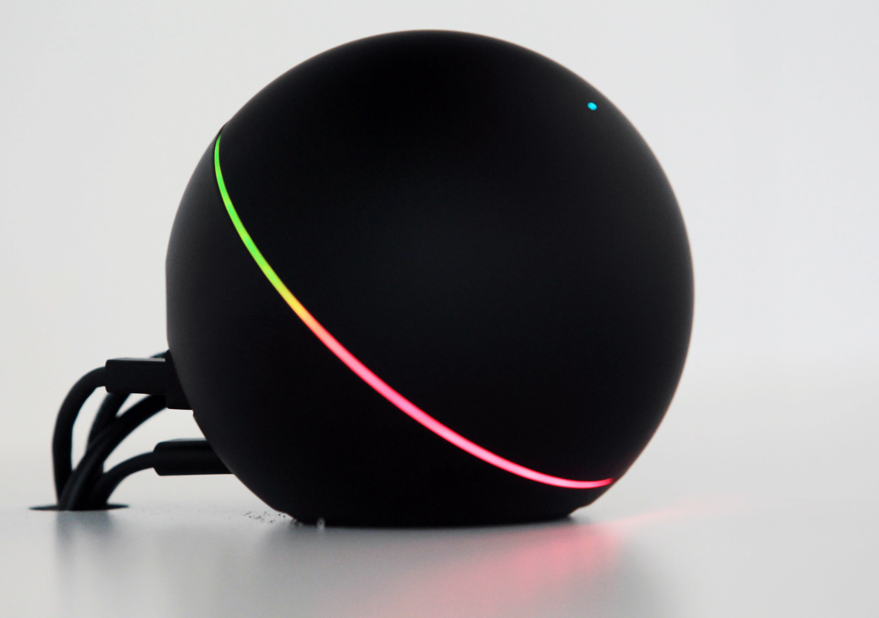 A Google Nexus Q with a multicolor LED ring on a white surface
